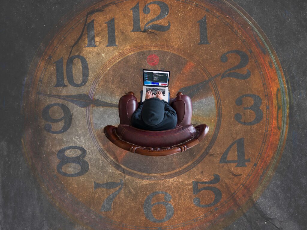 Person working on laptop with the big clock