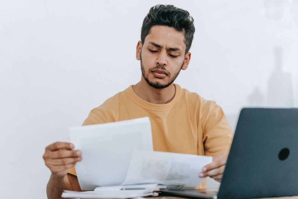 Man with laptop reading papers