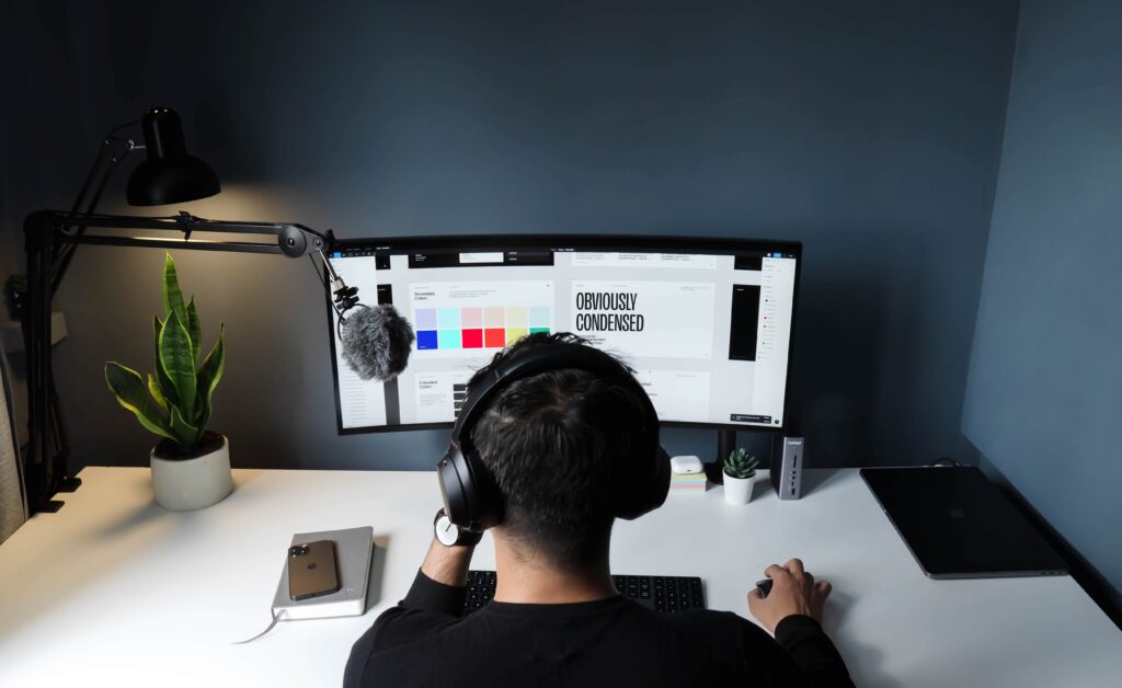 Man facing computer screen, wearing headphones, holding mouse