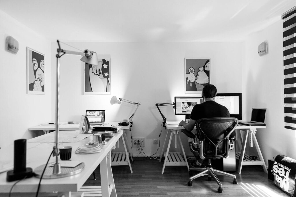 black and white animation studio with man working on computer. posters on walls