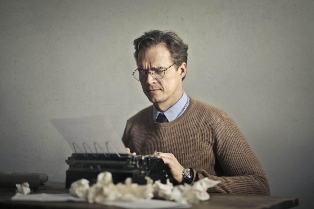 Man wearing glasses using a typewriter