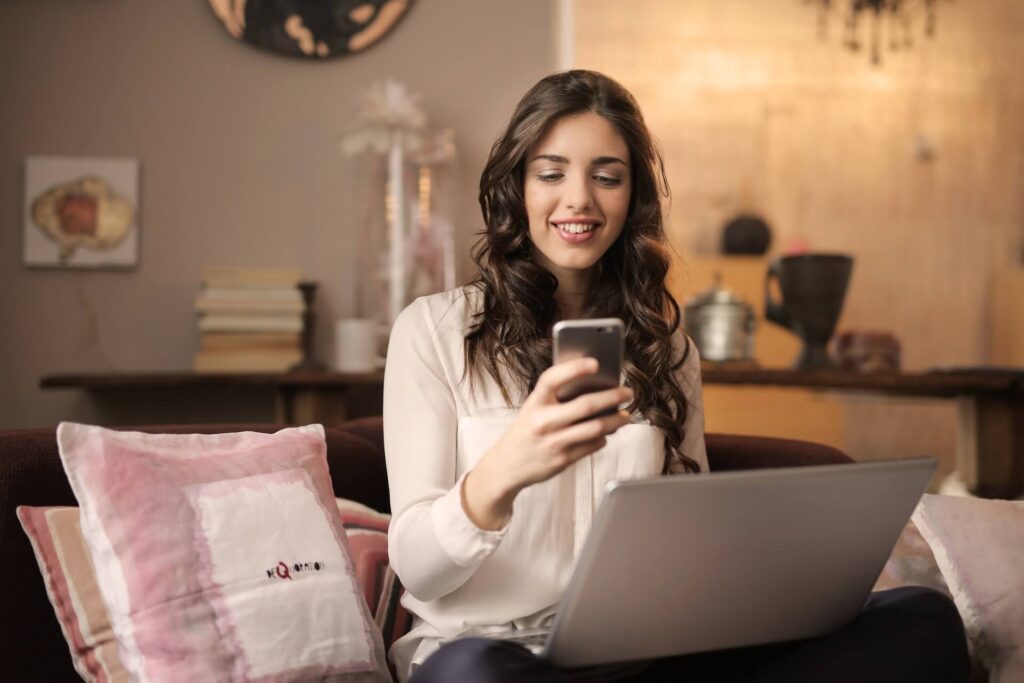 Woman using phone and laptop