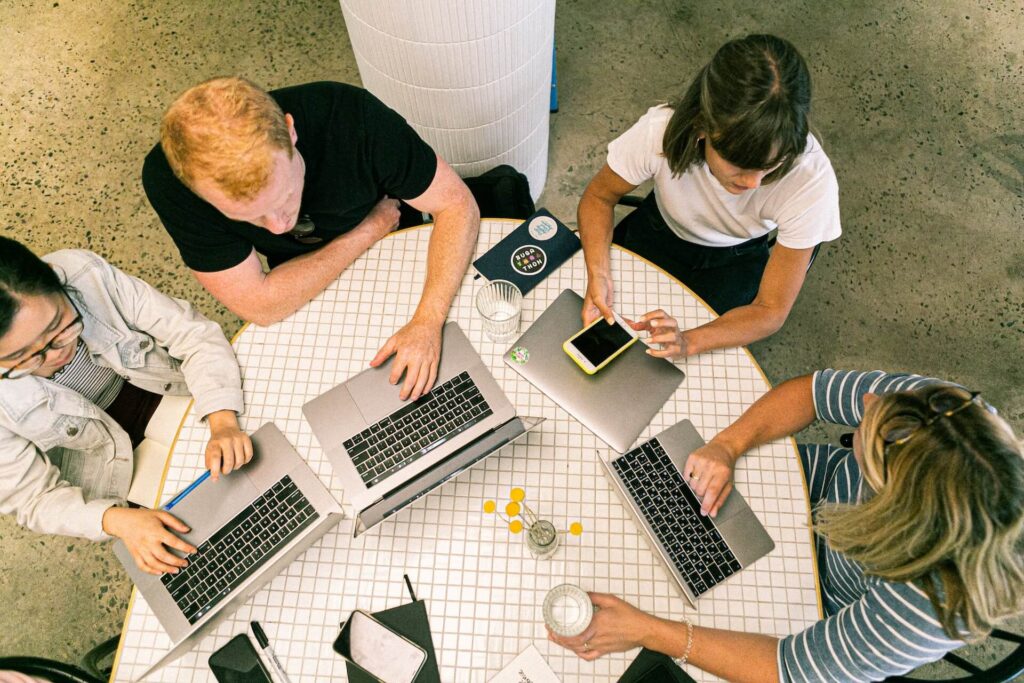 Group of people working on a table with laptops