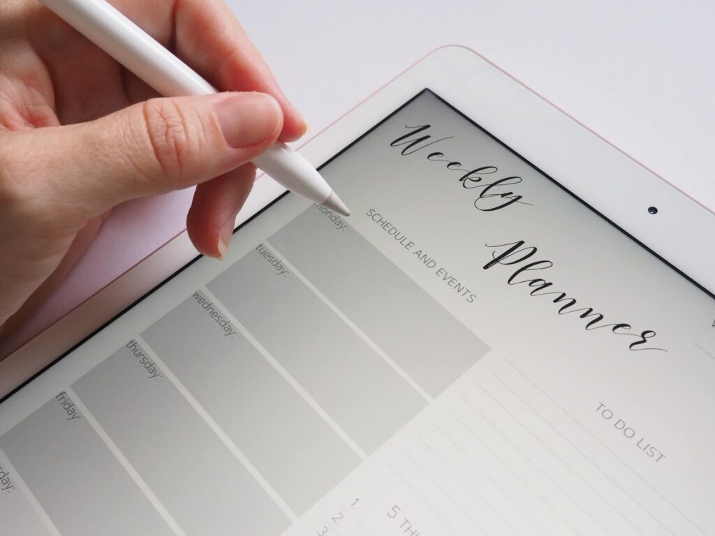 Weekly planner on a tablet, hand holding a stylus