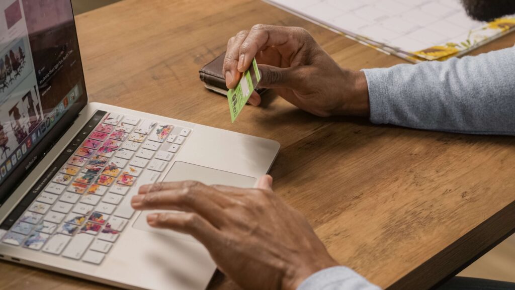 Person using laptop holding a credit card