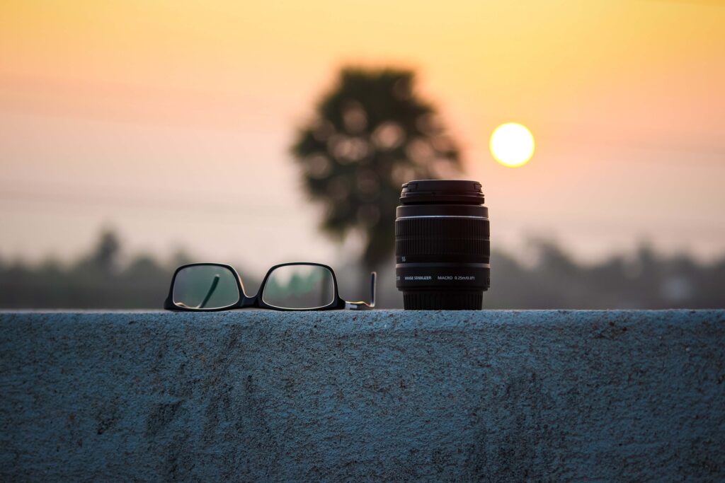 camera lens and eyeglasses with sun and tree background