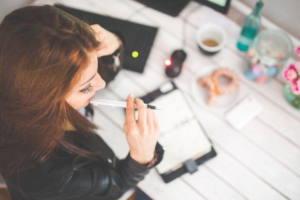 Woman with pen and notebook, thinking