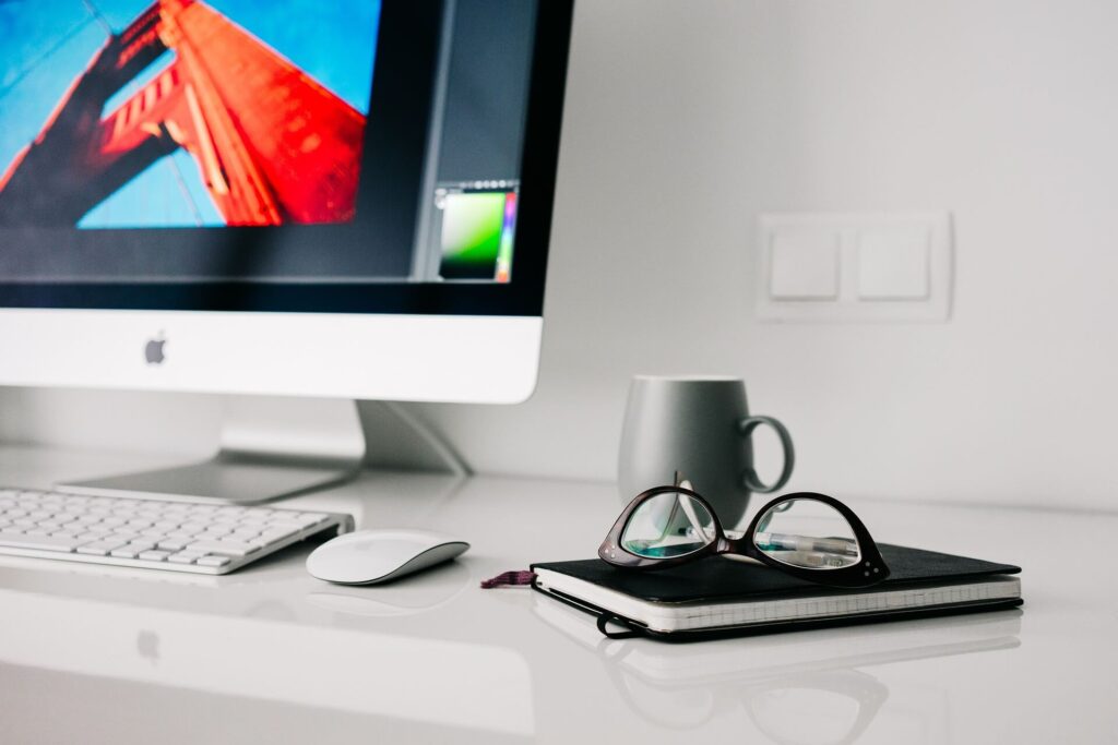 office desk with computer, notebook and glasses