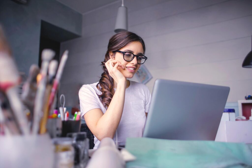 Woman wearing glasses smiling, using laptop