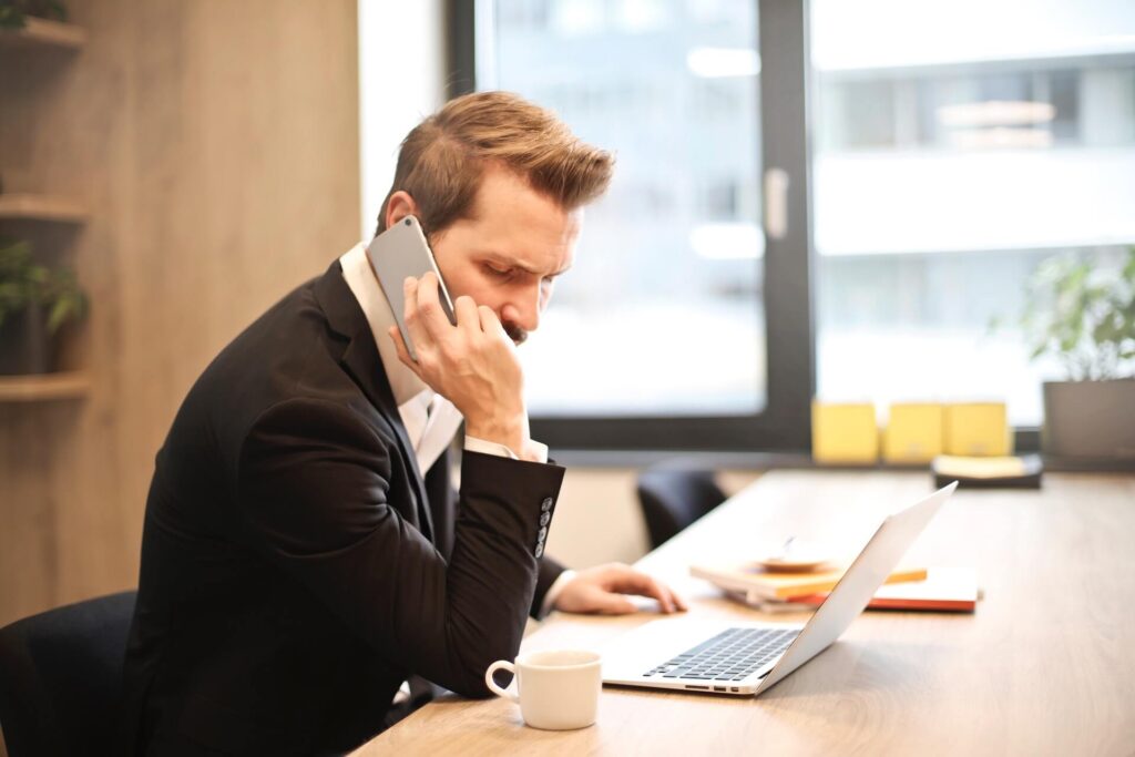 Man in a suit on the phone, using a laptop