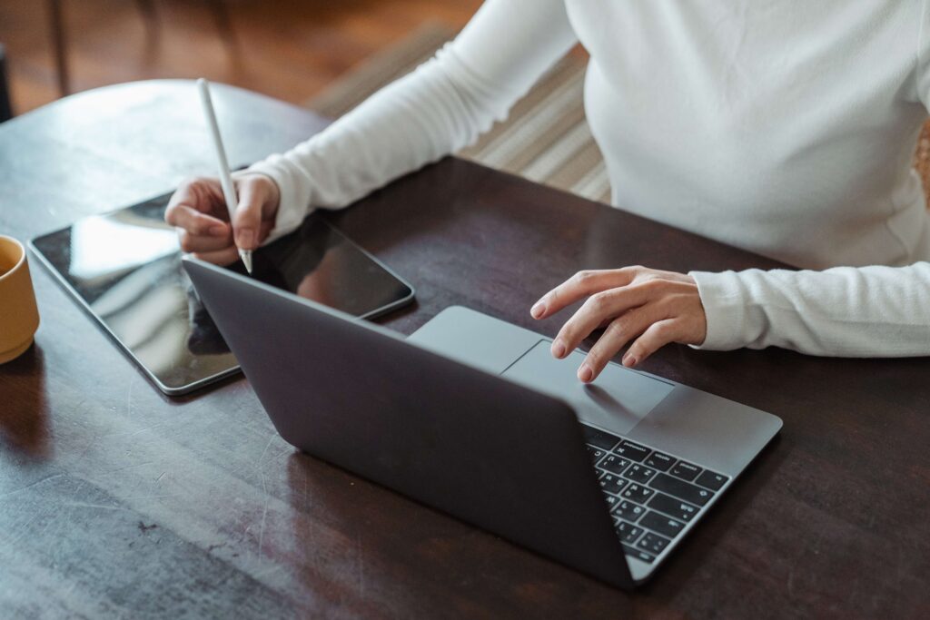 faceless woman working on laptop and tablet