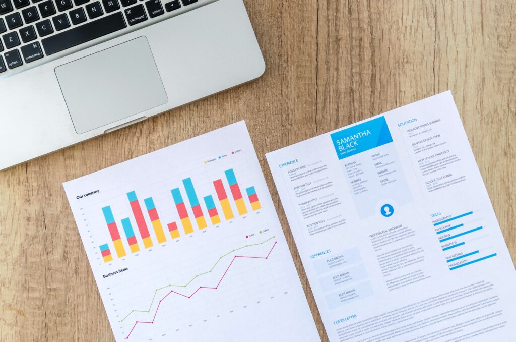 resume and charts printed on paper with laptop
