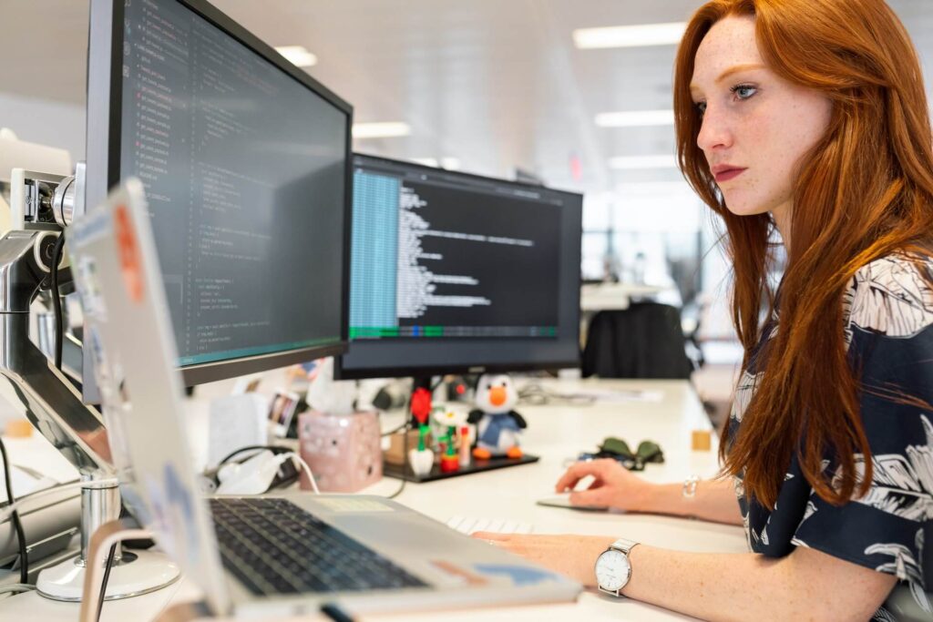 Woman working with 2 desktop monitors and 1 laptop