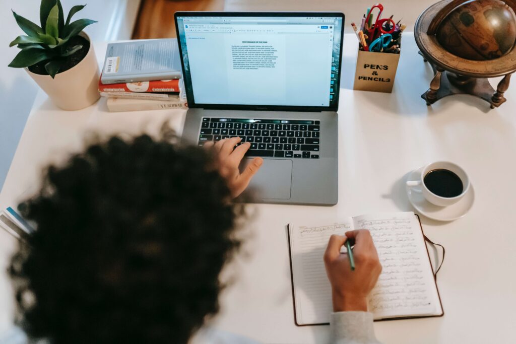 top view of writer with laptop and notebook