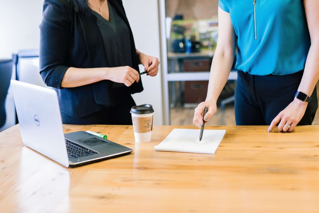 woman pointing a pen on paper with laptop and coffee on table