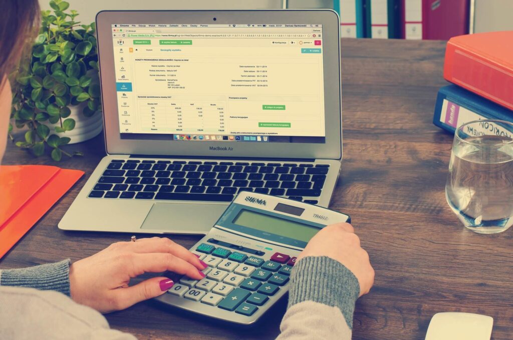 laptop on table showing an invoice with unidentified woman using calculator