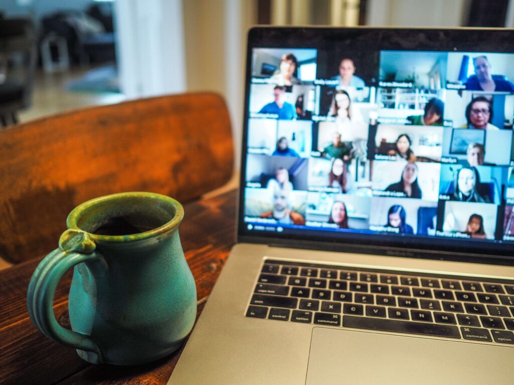 mug and laptop with blurred video conferencing on screen