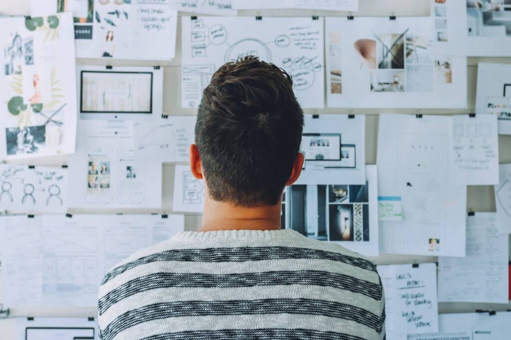 Man facing a board filled with papers and plans