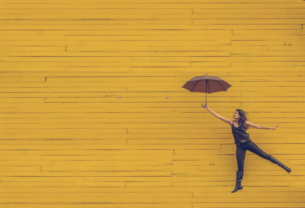 woman flying with an umbrella on yellow background