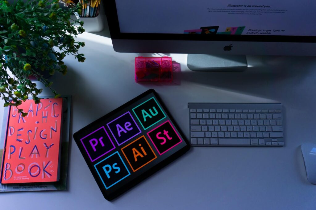 Desk with an tablet, book entitled Graphic Design Playbook, an iMac, keyboard, and mouse. 