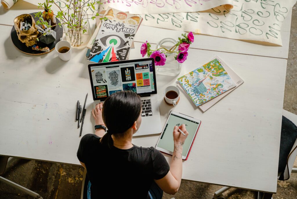 woman designing on tablet with laptop and messy table