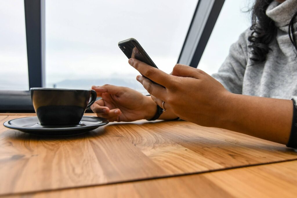 Person holding a coffee cup and a mobile phone