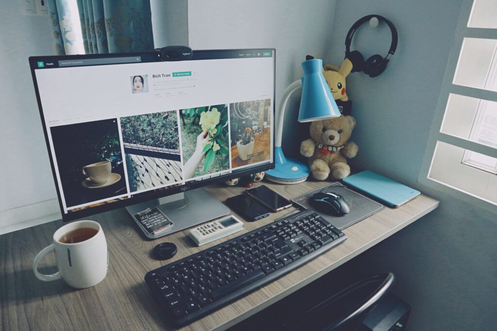 computer showing photos and a bio on a table with other things