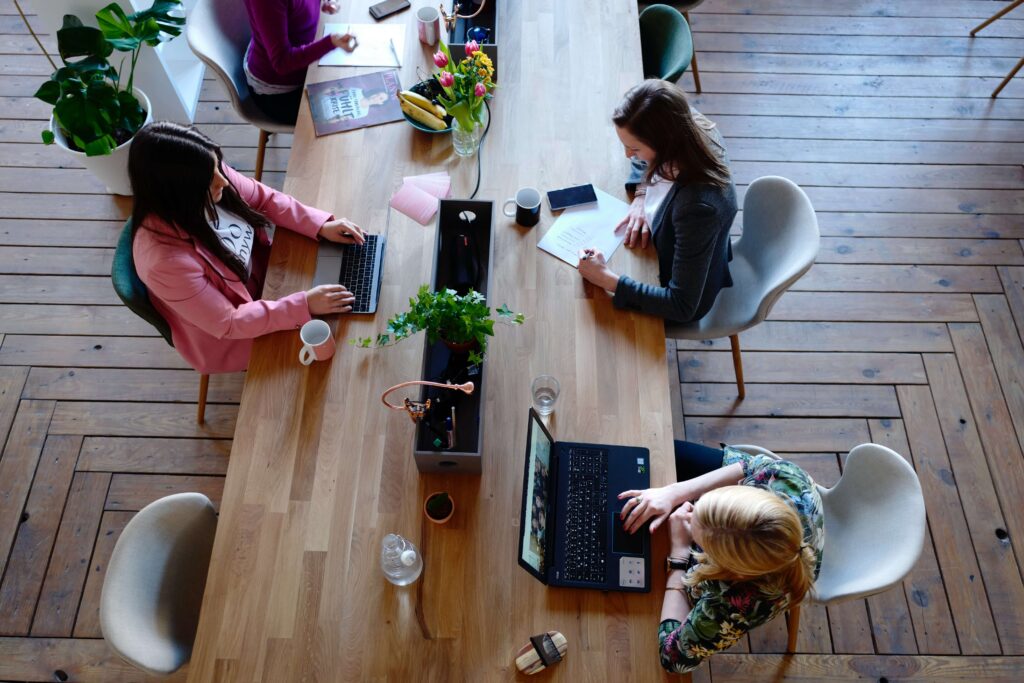 3 women working on a communal table at a coworking space