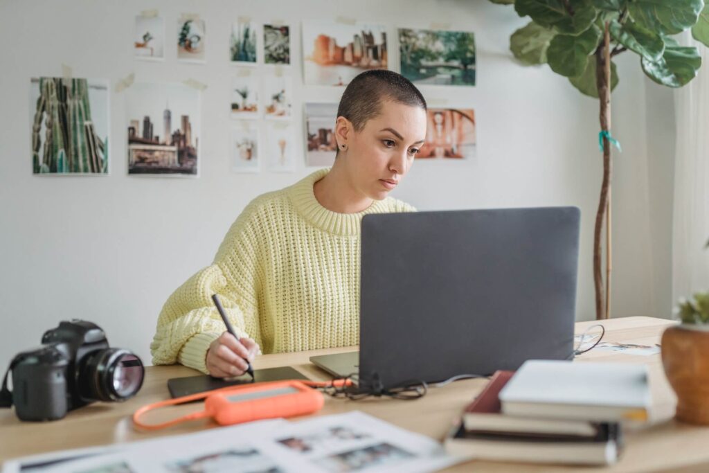 freelance designer looking at laptop, using a tablet with pen