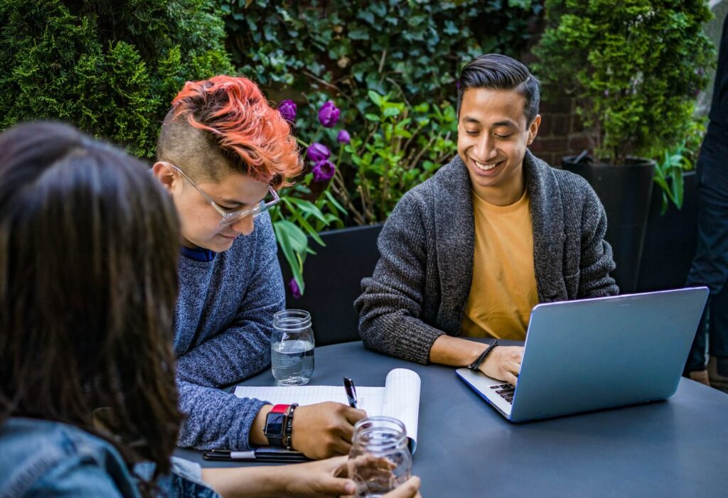 three people looking at paper with laptop on table