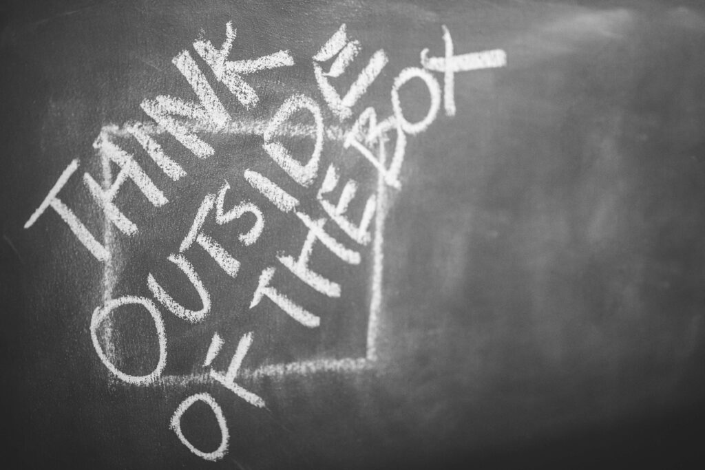 Think Outside of the Box written on chalk on a blackboard