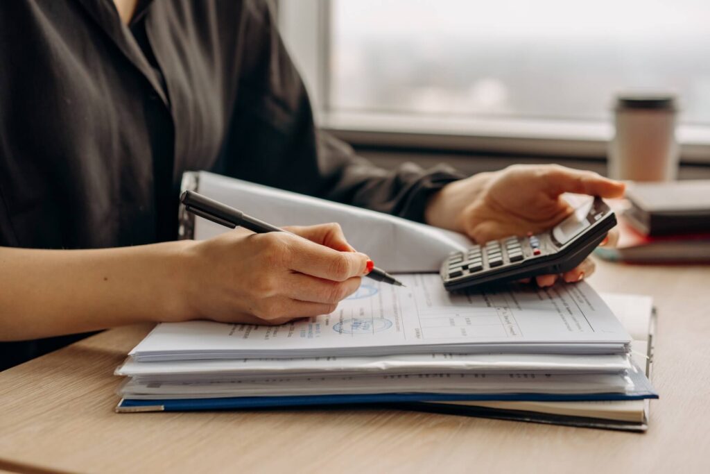 Person holding a calculator and a pen handling files