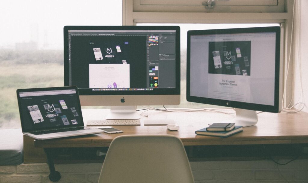 Desktop with two monitors and a laptop showing the same logo