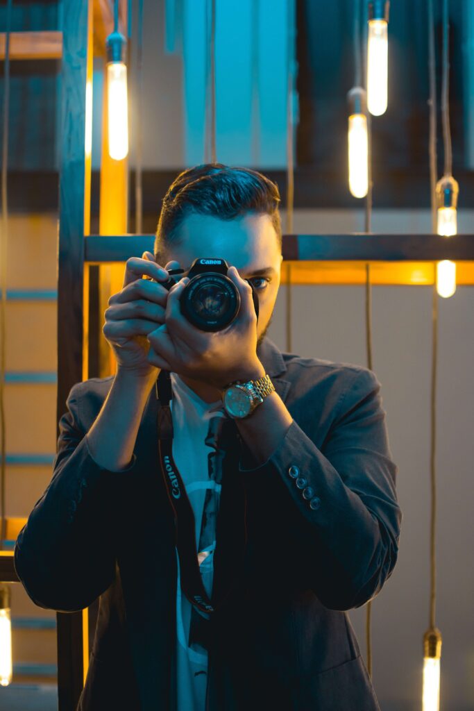 man on a suit holding a camera with lights on background