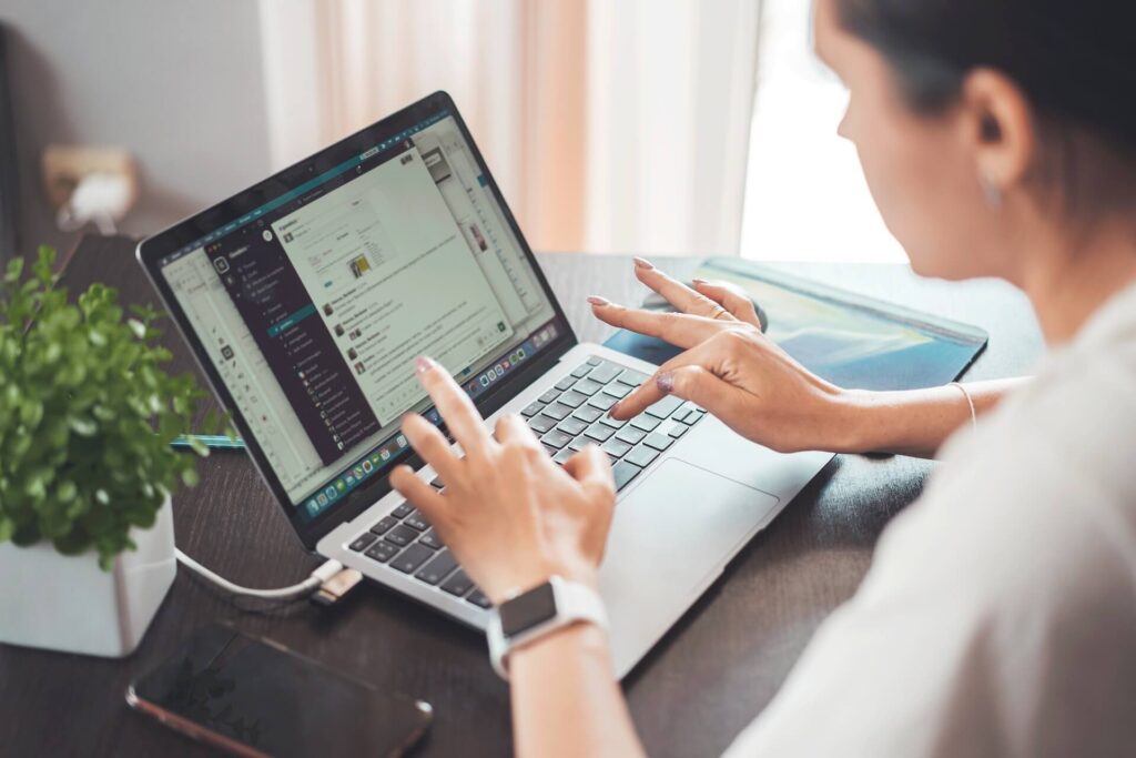 Woman typing on laptop showing Slack