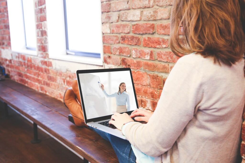 woman watching virtual class while sitting on bench