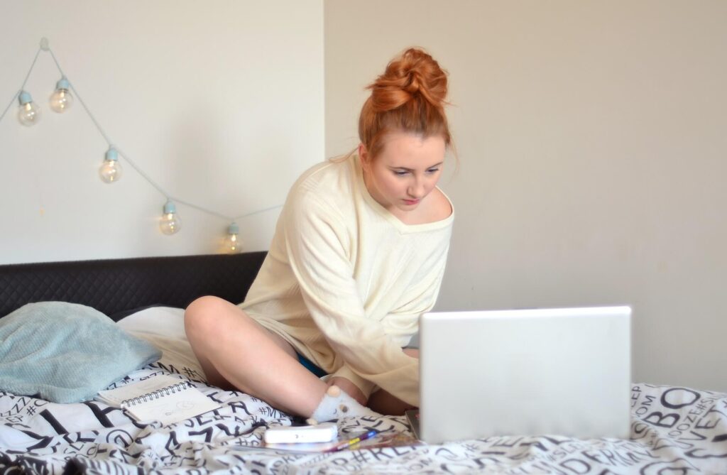 Woman working on laptop on bed