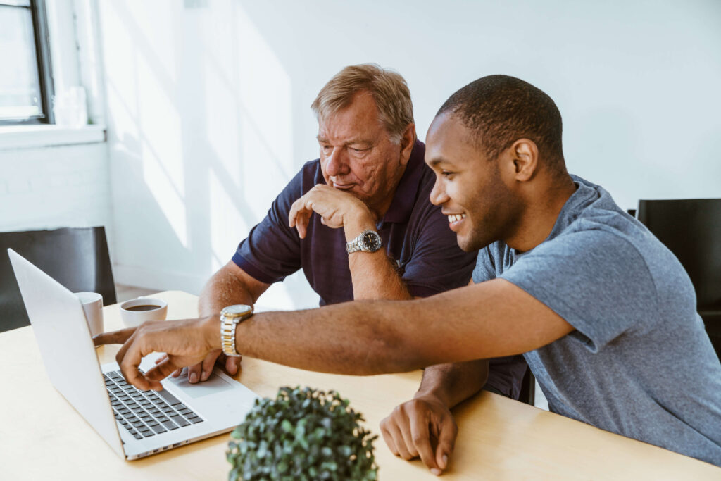 2 men discussing an item in laptop