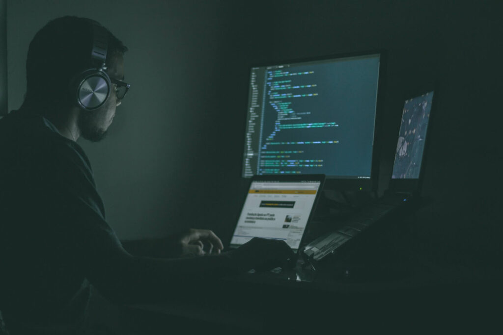 Programmer using two laptops and a monitor