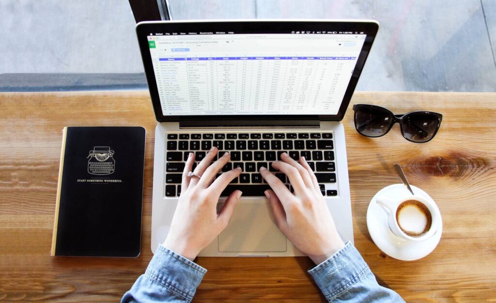 Person typing on laptop showing a spreadsheet