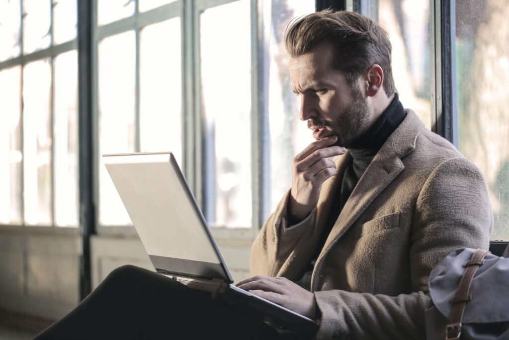 man looking confused reading laptop