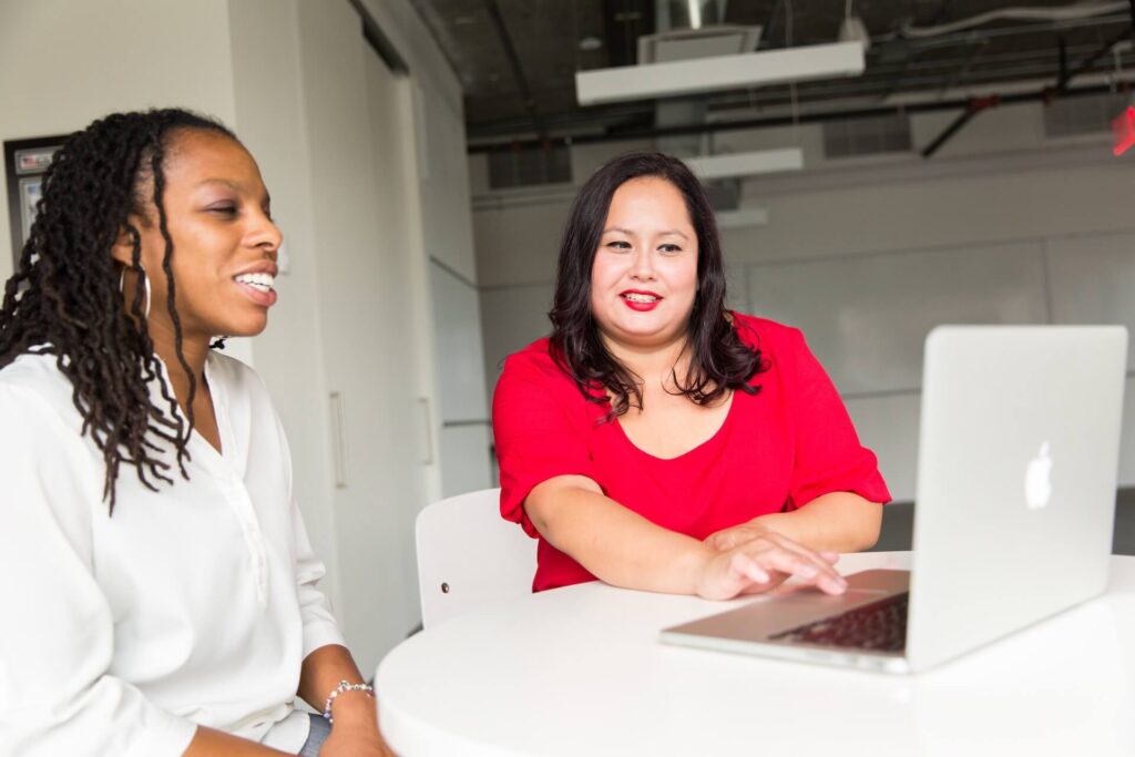 two women sitting in front of table with a laptop