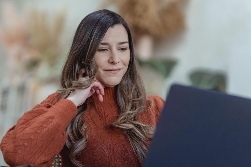 Woman with a small smile, looking at a laptop
