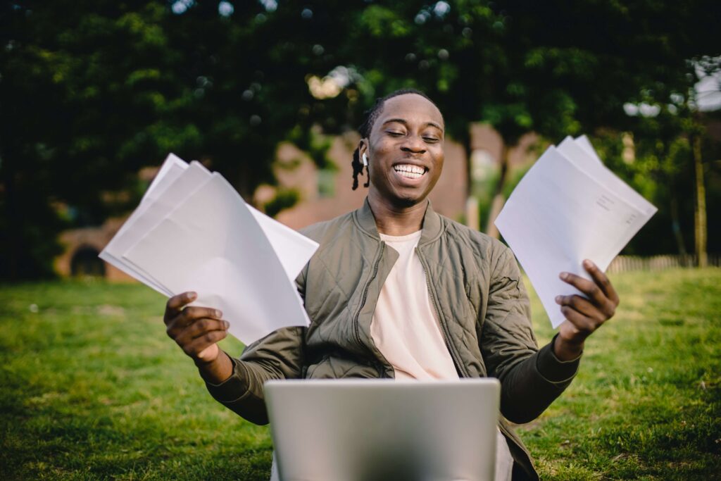 person smiling while looking at laptop and holding papers