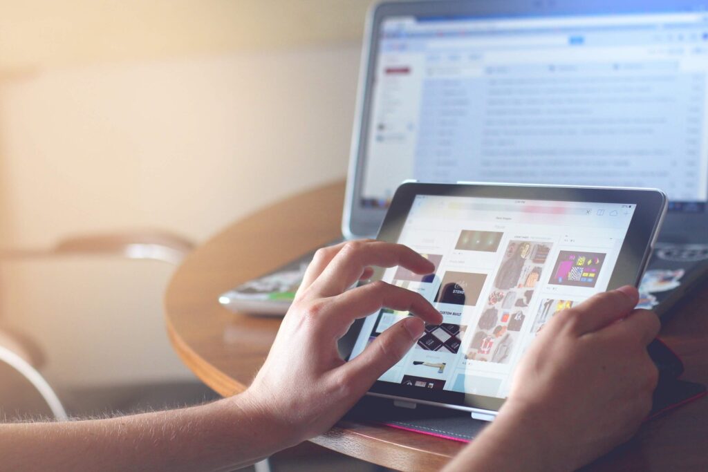 person touching a tablet with laptop on background