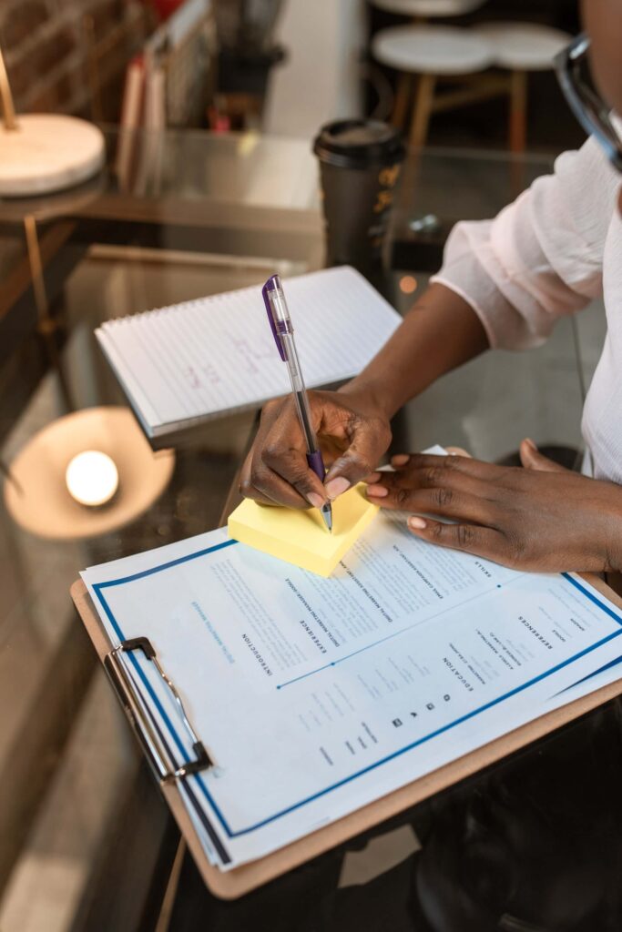 Woman writing on a post it, on top of a resume