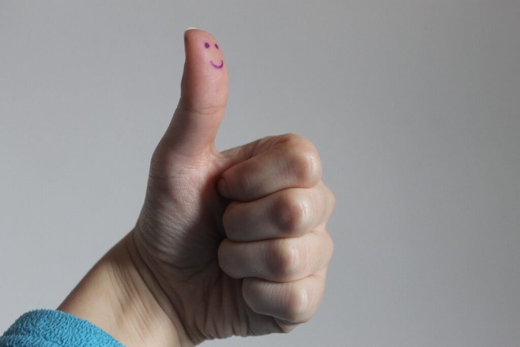 thumbs up with smiley face drawing on thumb